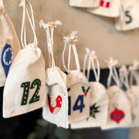 Decorative bags with numbers and Christmas-themed designs hanging on a wall.
