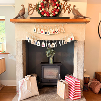 Decorative fireplace with Christmas wreath, stockings, and gift bags in a cozy living room.