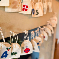 Decorative bags with numbers and symbols hanging on a string against a neutral background