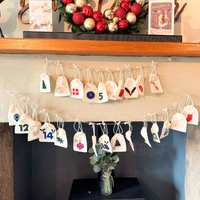 Decorative Advent calendar with numbered tags on a fireplace mantle.