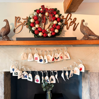 Decorative Christmas wreath with red and gold baubles on a mantelpiece above an advent calendar.