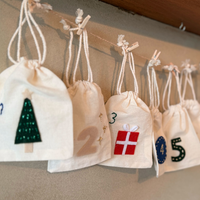 Decorative bags with numbers and festive designs hanging on a line.